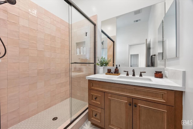 full bath with a shower stall, vanity, and visible vents