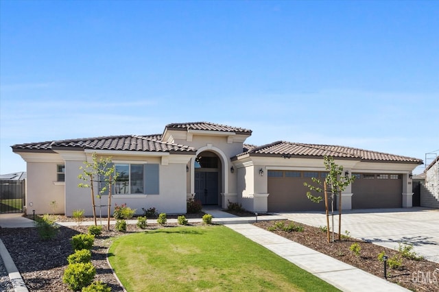 mediterranean / spanish-style home with a tile roof, a front lawn, concrete driveway, an attached garage, and stucco siding