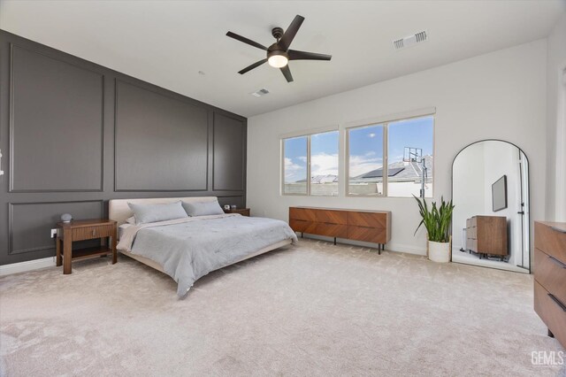bedroom with light colored carpet, ceiling fan, baseboards, and visible vents