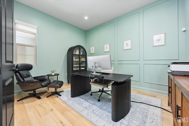office space featuring light wood-type flooring, recessed lighting, and a decorative wall