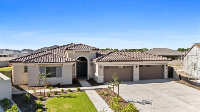 mediterranean / spanish home featuring an attached garage, a tiled roof, fence, and driveway