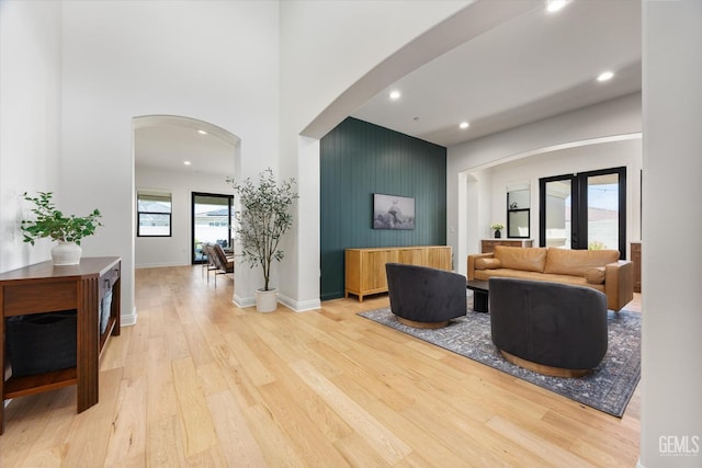 living area with wood finished floors, a high ceiling, and arched walkways