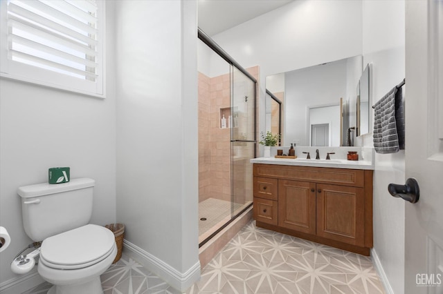 full bath featuring a shower stall, vanity, baseboards, toilet, and tile patterned flooring