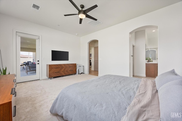 bedroom with radiator, arched walkways, visible vents, and light colored carpet