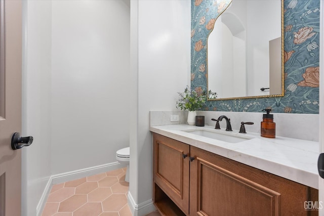 bathroom with toilet, vanity, tile patterned floors, and baseboards