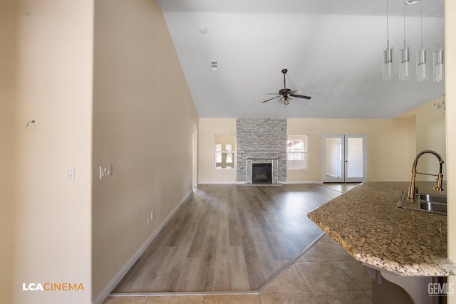 917 Newcastle Ct, Shafter, CA 93263 - unfurnished living room with a sink, a large fireplace, ceiling fan, baseboards, and high vaulted ceiling