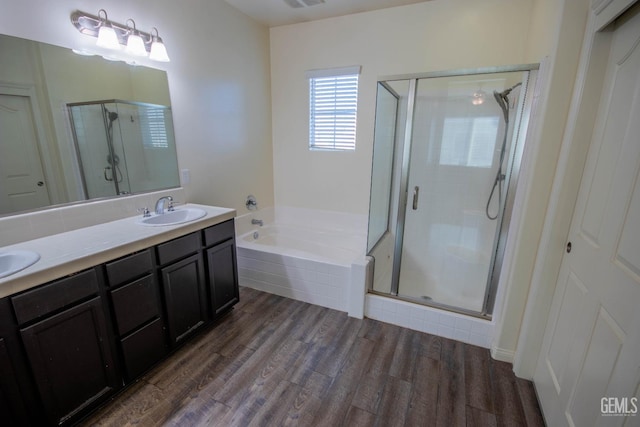 full bathroom featuring wood finished floors, a sink, a shower stall, a bath, and double vanity