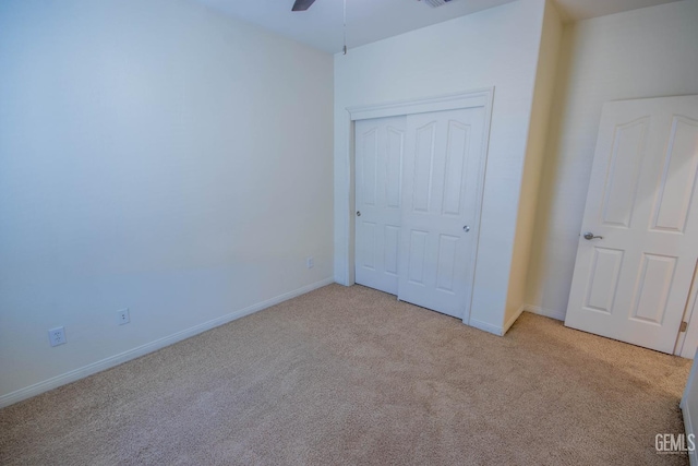 unfurnished bedroom featuring light carpet, a closet, and baseboards