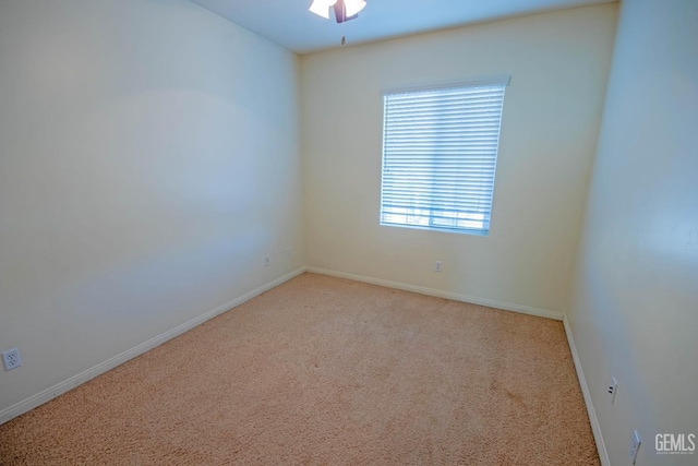 spare room featuring a ceiling fan, light carpet, and baseboards