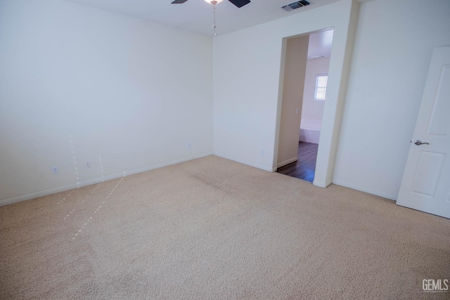 carpeted empty room featuring ceiling fan, visible vents, and baseboards