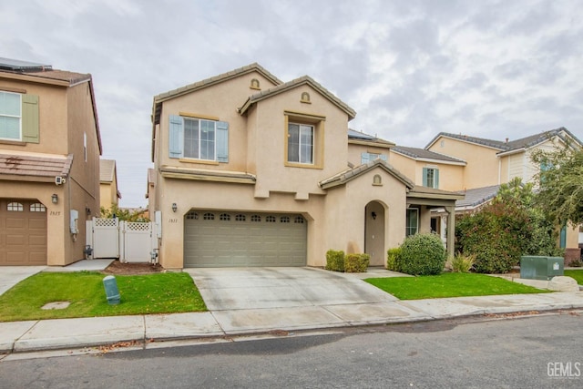 mediterranean / spanish-style home with stucco siding, an attached garage, a gate, driveway, and a tiled roof