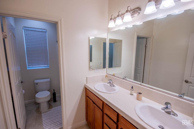 bathroom featuring double vanity, a sink, toilet, and baseboards