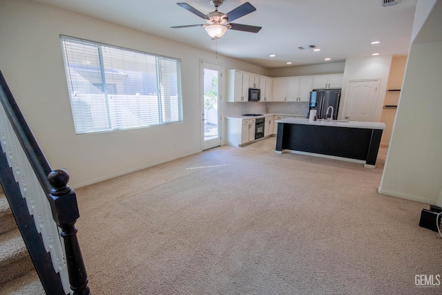 kitchen featuring tasteful backsplash, white cabinets, an island with sink, light countertops, and black appliances