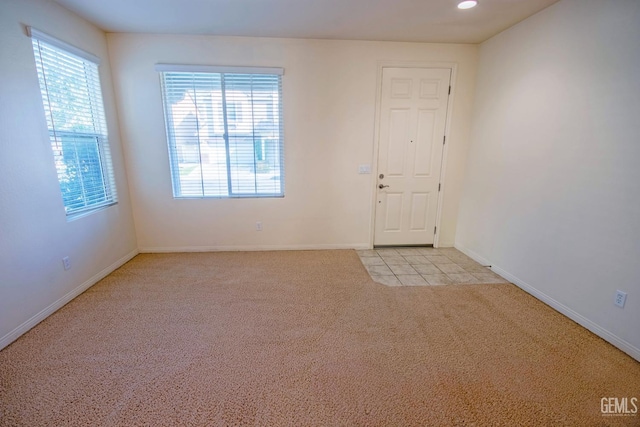 unfurnished room with light carpet, recessed lighting, and baseboards