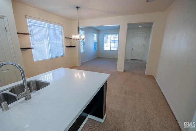 kitchen featuring light carpet, light countertops, a sink, and decorative light fixtures