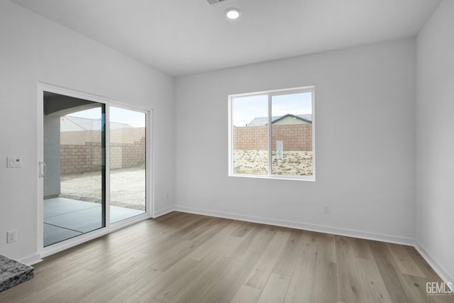 empty room featuring light wood-type flooring, visible vents, and baseboards