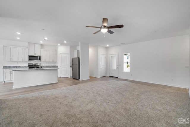 unfurnished living room with ceiling fan, baseboards, light wood-style flooring, and recessed lighting