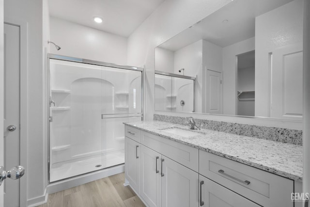 bathroom featuring a closet, a stall shower, wood finished floors, and vanity