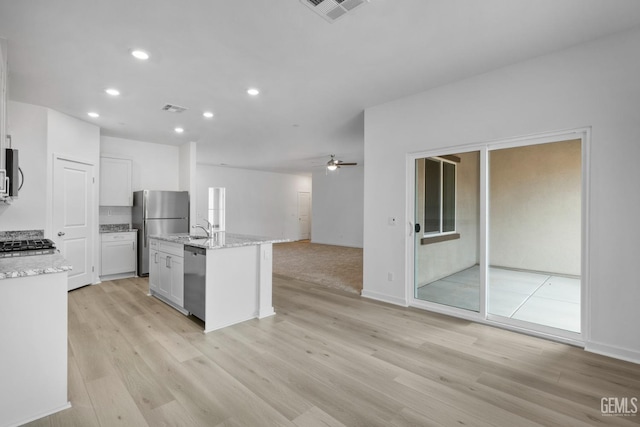 kitchen featuring light wood finished floors, appliances with stainless steel finishes, an island with sink, and visible vents