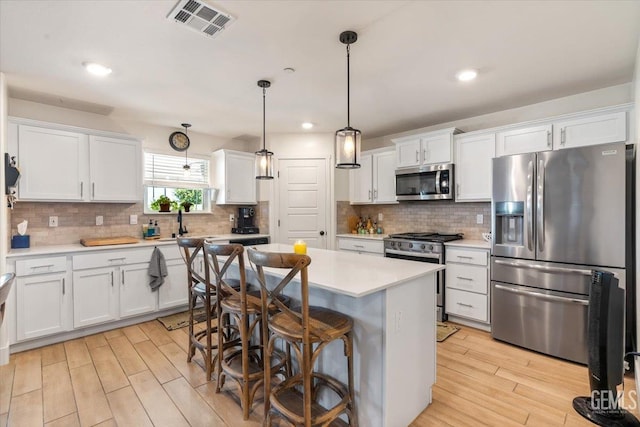 10026 Murfreesboro Dr, Bakersfield, CA 93311 - kitchen with appliances with stainless steel finishes, light wood-type flooring, white cabinets, light countertops, and a center island