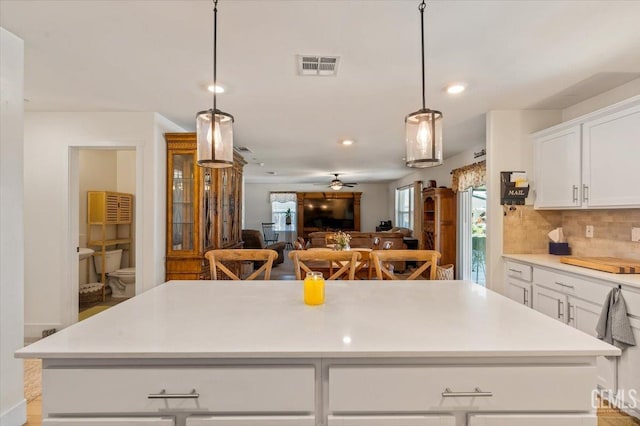 10026 Murfreesboro Dr, Bakersfield, CA 93311 - kitchen with tasteful backsplash, a kitchen island, white cabinets, light countertops, and decorative light fixtures