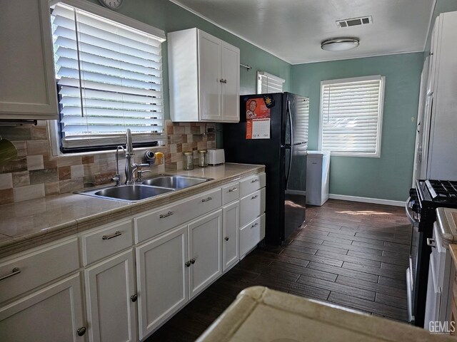 kitchen with appliances with stainless steel finishes, backsplash, stainless steel counters, sink, and white cabinetry