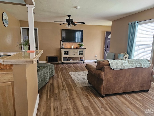 living room with decorative columns, hardwood / wood-style floors, and ceiling fan