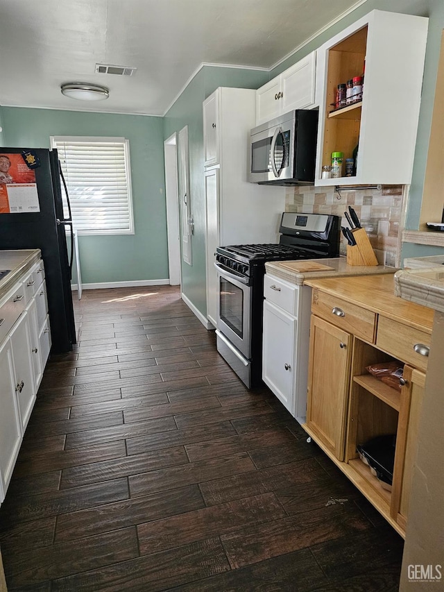 kitchen with dark hardwood / wood-style flooring, backsplash, white cabinets, and appliances with stainless steel finishes