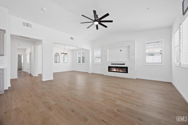 14610 Coyle Cir, Bakersfield, CA 93311 - unfurnished living room featuring a glass covered fireplace, a ceiling fan, light wood-style floors, a chandelier, and vaulted ceiling