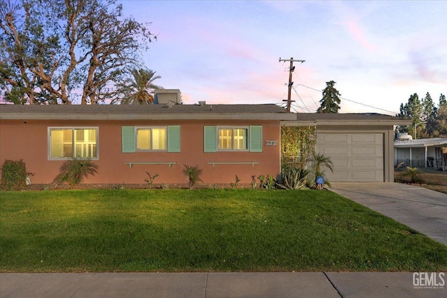 single story home featuring a lawn and a garage