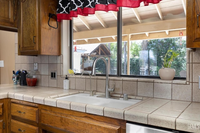 6801 Weldon Ave, Bakersfield, CA 93308 - kitchen featuring a sink, decorative backsplash, brown cabinets, beam ceiling, and light countertops