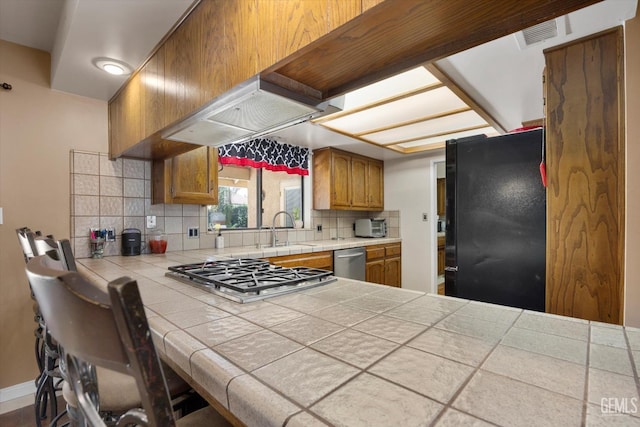 6801 Weldon Ave, Bakersfield, CA 93308 - kitchen with appliances with stainless steel finishes, a sink, tile countertops, backsplash, and brown cabinets