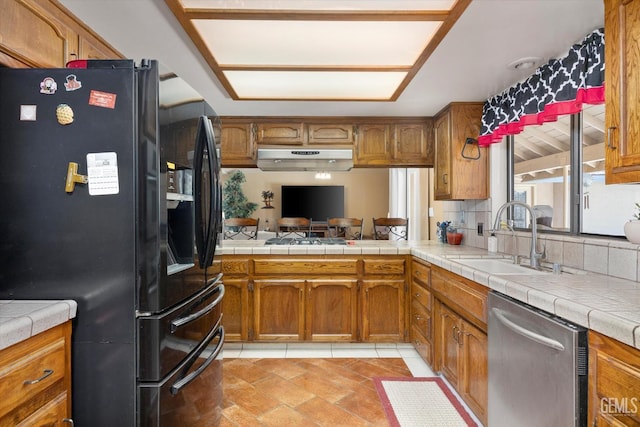 6801 Weldon Ave, Bakersfield, CA 93308 - kitchen featuring black fridge with ice dispenser, dishwasher, a sink, brown cabinets, and under cabinet range hood