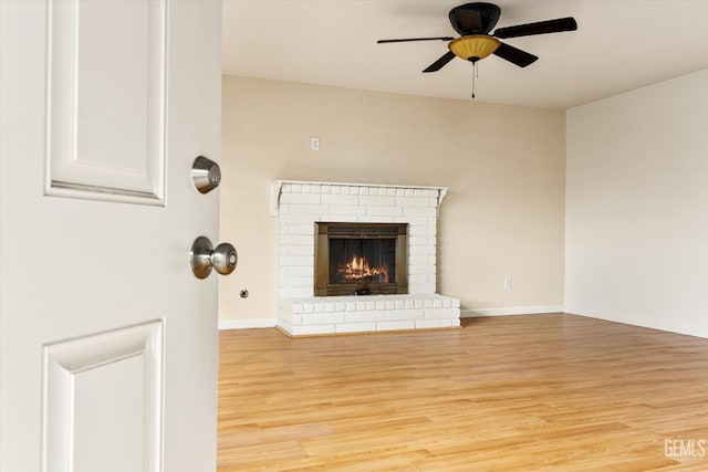 unfurnished living room with light wood-type flooring, a fireplace, baseboards, and ceiling fan