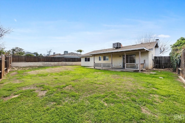 back of house with a yard, central air condition unit, a fenced backyard, and stucco siding