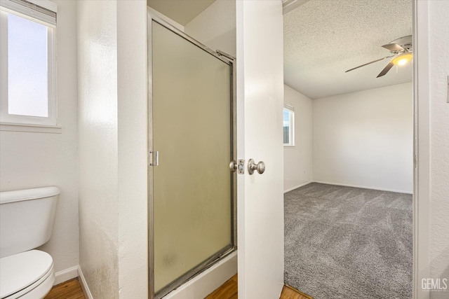 full bathroom with toilet, a shower stall, a ceiling fan, and a textured ceiling