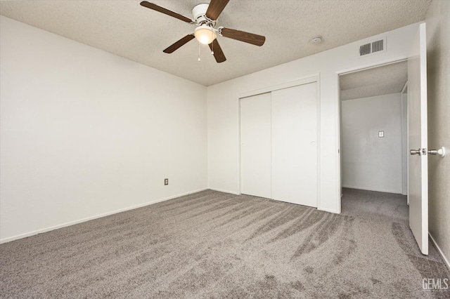 unfurnished bedroom featuring a textured ceiling, carpet floors, a closet, and visible vents