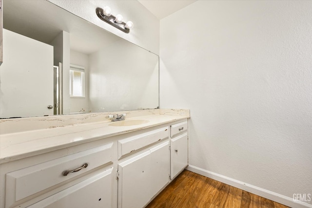 bathroom featuring baseboards, wood finished floors, and vanity