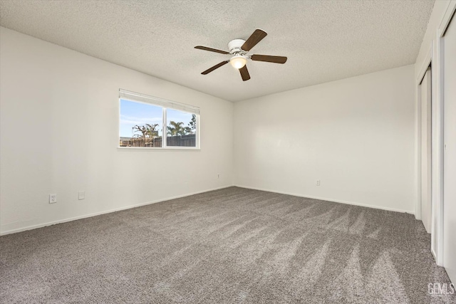 interior space featuring a textured ceiling, dark colored carpet, and a ceiling fan