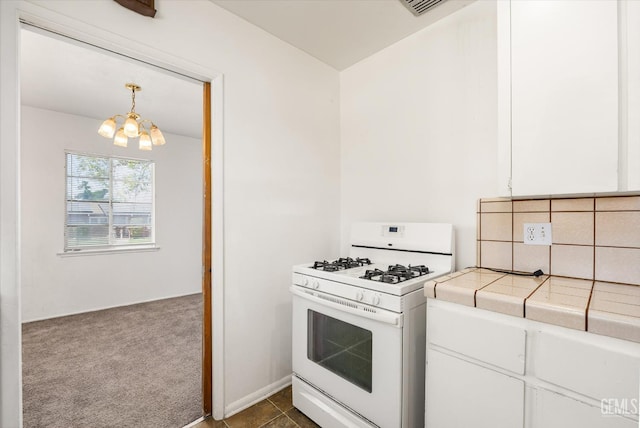 3201 Pomona St, Bakersfield, CA 93305 - kitchen featuring white gas range oven, tile counters, a chandelier, dark colored carpet, and white cabinetry
