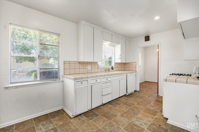 3201 Pomona St, Bakersfield, CA 93305 - kitchen featuring tile counters, white dishwasher, dark stone finish flooring, backsplash, and white cabinetry