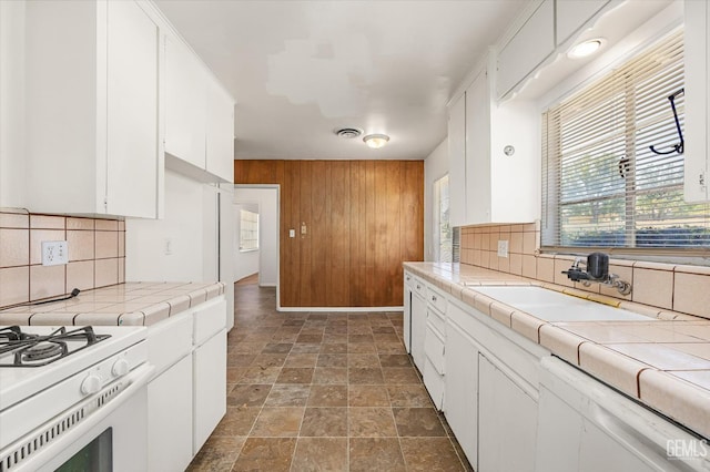 3201 Pomona St, Bakersfield, CA 93305 - kitchen with tile countertops, dishwashing machine, wood walls, stone finish floors, and tasteful backsplash