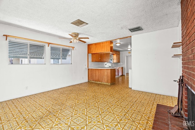 102 Wetherley Dr, Bakersfield, CA 93309 - kitchen featuring brown cabinets, light countertops, a peninsula, ceiling fan, and a fireplace
