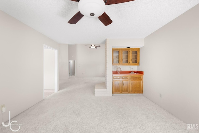 interior space with a sink, ceiling fan, wet bar, and light colored carpet