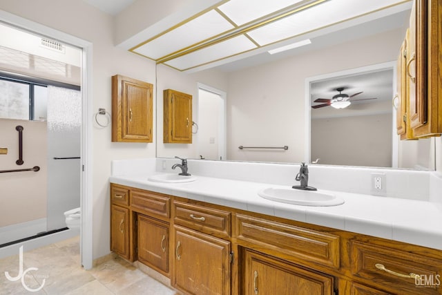 bathroom with a sink, ceiling fan, toilet, and double vanity