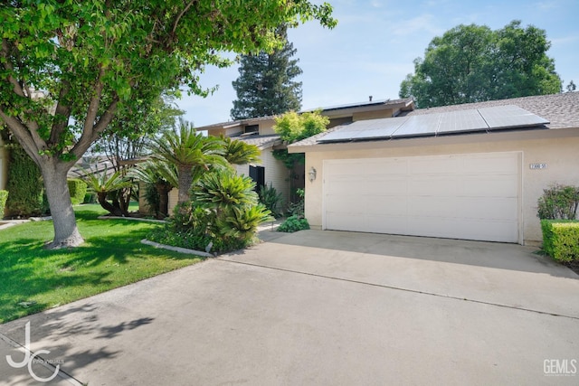 ranch-style home with a garage, roof mounted solar panels, a front lawn, concrete driveway, and stucco siding
