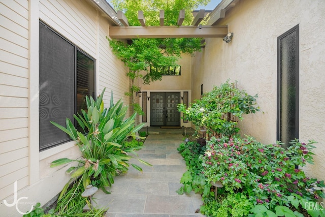 view of exterior entry featuring french doors and stucco siding