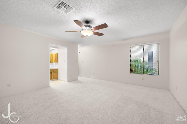 empty room with visible vents, a ceiling fan, a textured ceiling, and carpet floors