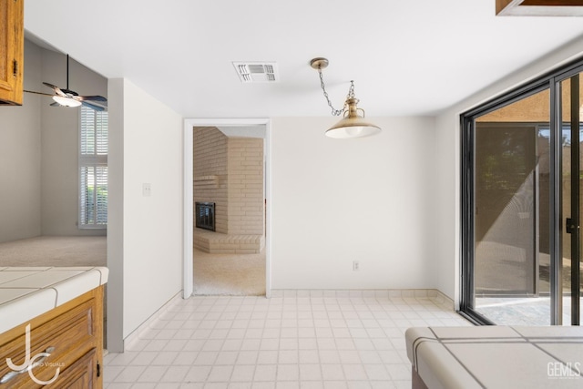 interior space with baseboards, ceiling fan, a fireplace, and visible vents
