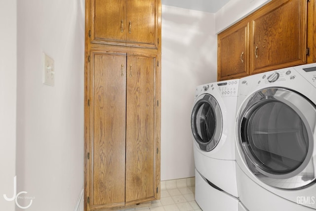 clothes washing area featuring washing machine and dryer and cabinet space